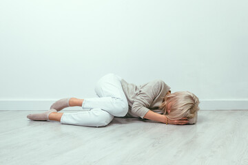 A young girl lies curled up on the floor. Depression concept.