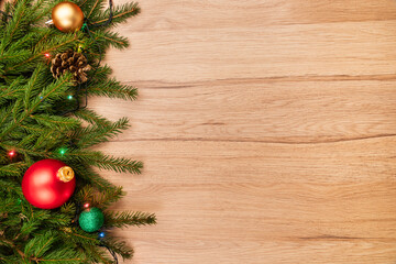 Christmas background with fir branches baubles and lights on wooden board