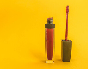 bright matte lip gloss on a yellow matte background. transparent, compact tube with red, berry lipstick. lipstick for girls lips, comfortable shape for cosmetic bag