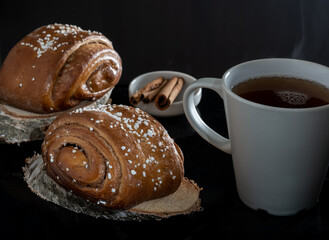 Closeup of traditional Finnish cinnamon rolls on top of wooden coasters. Cinnamon sticks.