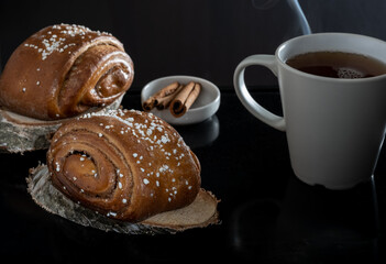 Closeup of traditional Finnish cinnamon rolls on top of wooden coasters. Cinnamon sticks.