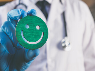 Patient Experience concept. The doctor is holding a smiley as symbol of satisfaction.