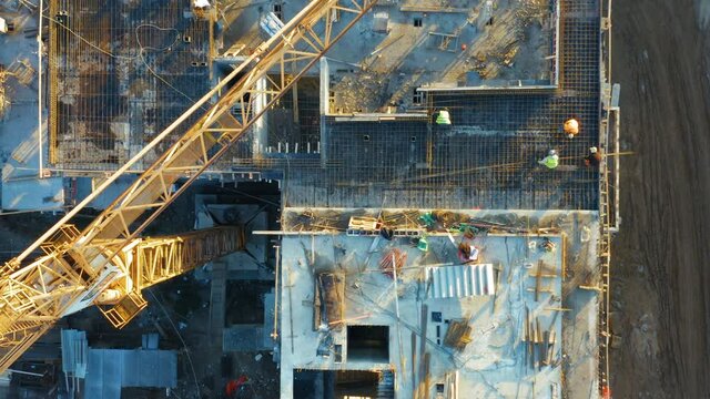 Aerial top down view of a construction site of with an apartment building under construction with tower crane and workers