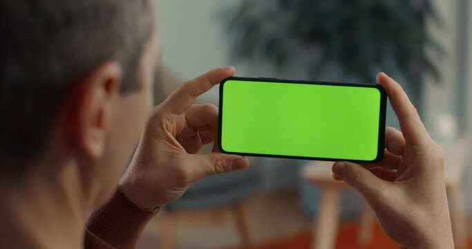 Caucasian man using smartphone with green empty screen