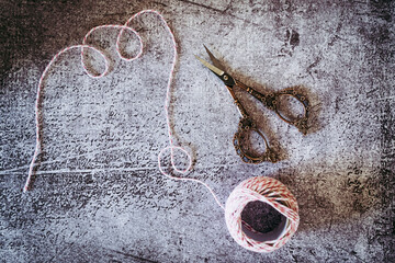 Ciseaux de couture en métal et bobine de fil blanc et rose pour emballer les cadeaux sur un fond gris vintage