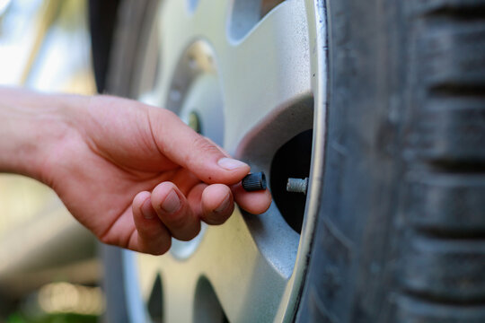 The hand twists or unscrews the nipple cap from the car wheel. Place the air replenishment tires.