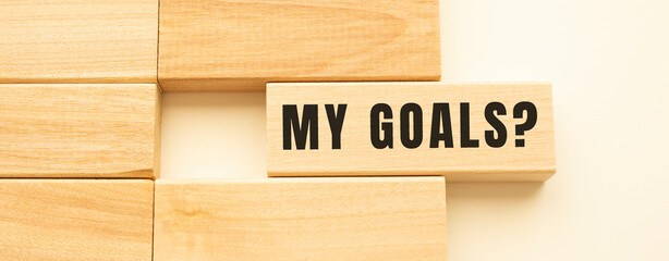 MY GOALS text on a strip of wood lying on a white table.