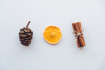 Obraz na płótnie Canvas Holiday flat lay with natural decorations such as pine cones, cinnamon sticks, dry orange slices on white wooden background. Zero waste Christmas concept. Plastic free holidays. Sustainable lifestyle.