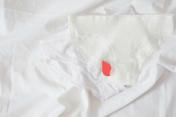 White cotton panties for women with red paper drops like red blood. Concept of menstruation