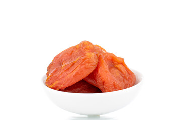 Bright orange organic dried apricots with ceramic dishes, close-up, isolated on white.