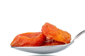 Bright orange organic dried apricots with a metal spoon, close-up, isolated on white.