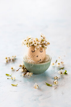 An Easter egg with a face and flower petals