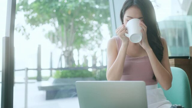 young attractive asian female wear casual cloth hand use smartphone and laptop device comminication social contact in cafe restaruant sit at counter next to big window daylight