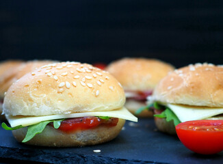 Burger with fresh herbs, ketchup, cheese and ham. Close-up