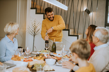 Young man opening bottle of red wine during at home