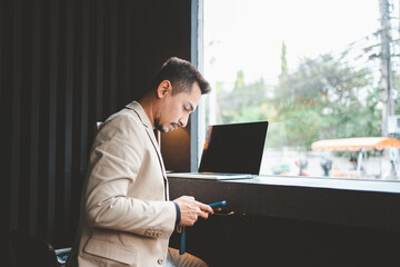 Young businessman using phone while working in cafe.