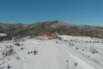 Scenic valley of hilghland alpine mountain winter resort on bright sunny day. Wintersport scene with people enjoy skiing and snowboarding on groomed pisets. panoramic wide view of downhill slopes