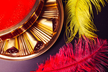 box of chocolates and two yellow and red feathers on a black background