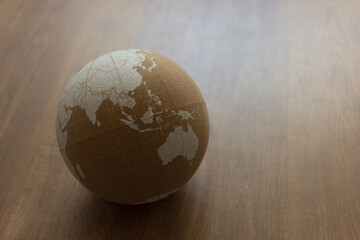 cork world ball with white political map on brown wooden background slightly rotated and shifted to...