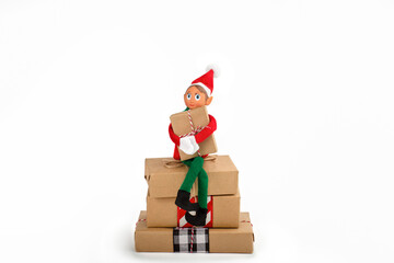Christmas Elf  sitting on a stack of gift boxes on an isolated  white background with copy space. Christmas spirit, Christmas family tradition.