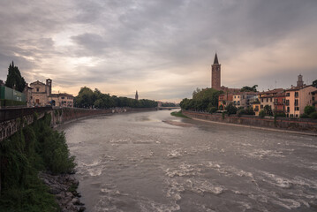 City landscape with the old town buildings along the bank of the Adige river in a stormy day,...