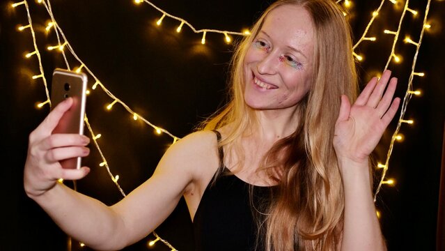 Lesbian, woman, bisexual, albino with rainbow makeup speaks on a video call and celebrates Merry Christmas and Happy New Year, gay parade, Bisexuality Day or National Coming Out Day in the month of