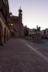 View of the main square of the medieval city of Trujillo with the Catholic Church of San Martin in gothic style and the equestrian statue of Francisco Pizarro at sunrise, Caceres, Extremadura, Spain