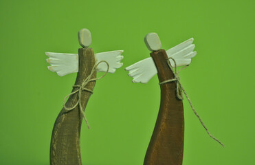 wooden angels with white wings. old angel figurine in a curved pose on a green background. isolated...