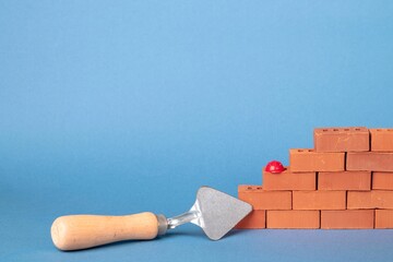 Blocks of red bricks, masonry trowel on a gray-blue background. Construction concept