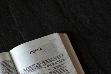 Open Holy Bible Book Hosea prophet from Old Testament on dark granite background. A Christian...