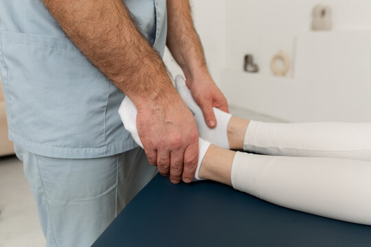 Knee pain relief in clinic. Doctor physiotherapist doing healing treatment on patient leg. Therapist giving leg and calf massage. Osteopathy, Chiropractic leg adjustment. Chiropractic treatment.