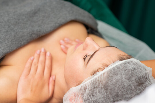 Massaging female chest. Young beautiful caucasian woman with closed eyes getting chest massage at beauty spa salon