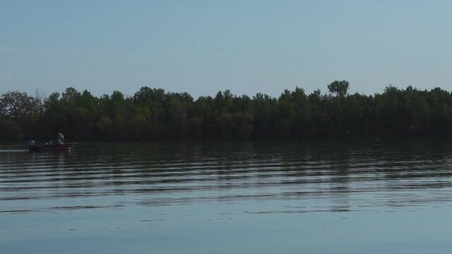 Fishing in the lake; a small rowboat comes into view on quiet, calm clear early morning lake water; grey blue early morning with clear skies. Northern Michigan. 401