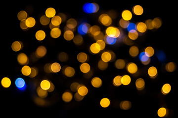 Perfect bokeh for a festive New Year and Christmas background. Defocused abstract yellow and blue light circles. Bokeh is distributed throughout the frame