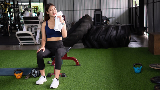 Attractive Asian Healthy Woman In Fitness Gym Taking A Rest After Work Out. Sport Exercise Concept.