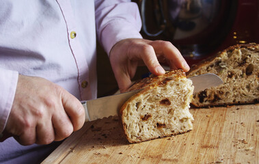 Man cutting fresh homemade organic bread for morning breakfast