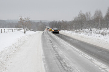 Cars drive with caution on the icy winter road.