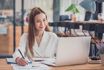 Asian woman sitting at a desk working in the office use a computer, laptop