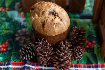 delicious Italian panettone with pine cones on the side, on a tablecloth decorated for Christmas, Christmas decoration, photo seen from above