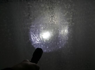 Lichtschein einer Taschenlampe trifft auf Duschvorhang