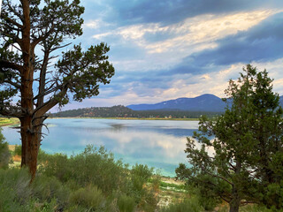 Fototapeta na wymiar mountain lake with overcast blue sky and reflective shoreline scene