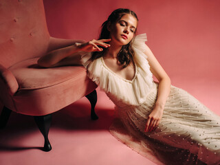 Beautiful brunette lady in ivory flattering dress on salmon background. Amazing bride with pink...