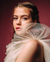Fototapeta premium Beauty portrait. Beautiful brunette young woman in ivory flattering dress on red background.