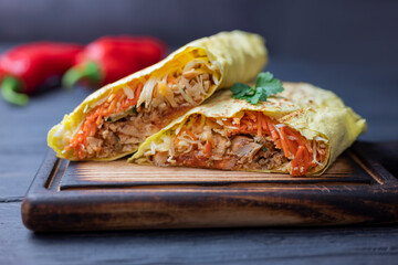 delicious fast food shawarma in pita bread with vegetables and pork and veal on a wooden board