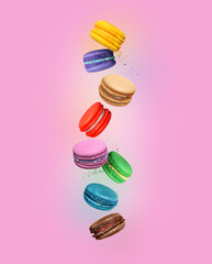 Сolored macaroons with different flavors in the air on pink background
