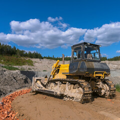 Obraz premium the process of leveling the soil with a modern bulldozer during the construction of a dirt road
