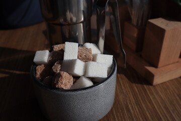 Ceramic bowl with white and brown sugar on the table.