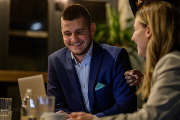 Cheerful work colleagues working on a laptop while having a meeting in a cafe