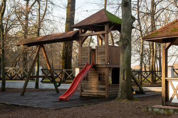 Wooden playground with a slide outside the city on an autumn morning.