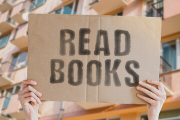 The phrase " Read books " on a banner in men's hand with blurred background. Routine. Success. Money. Business. Successful. Inspiration